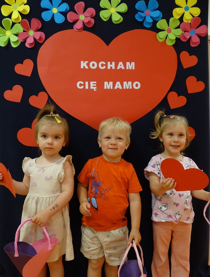 Dziewczynki oraz chłopiec trzymają prezenty dla swoich mam