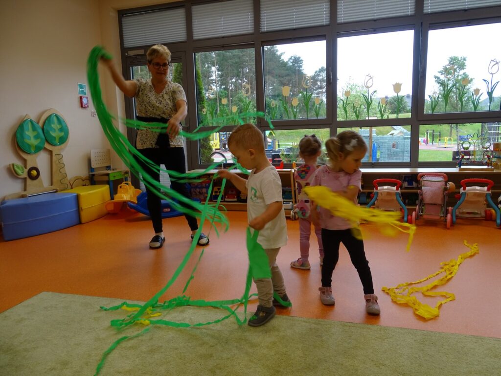 Dzieci wraz z Panią bawią się bibułą