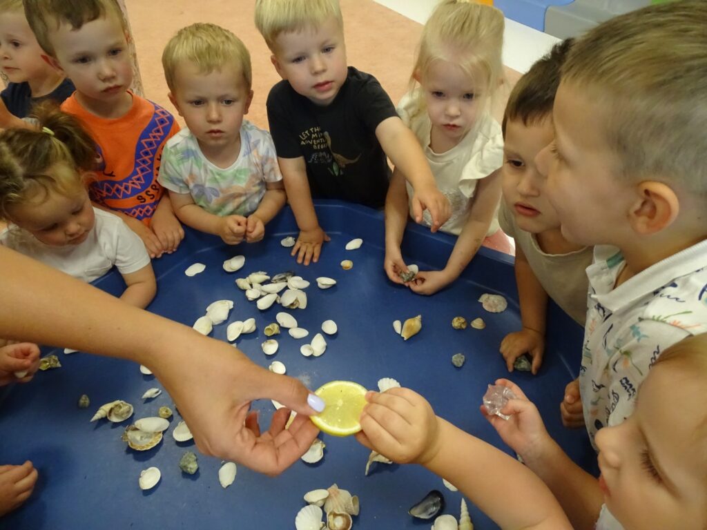 Opiekunka pokazuje dzieciom plasterki cytryny