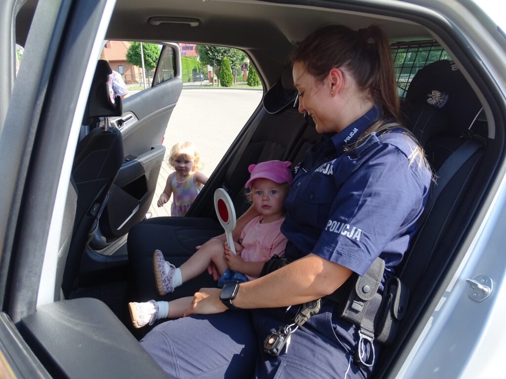  Pani policjant siedzi z dziewczynką w aucie
